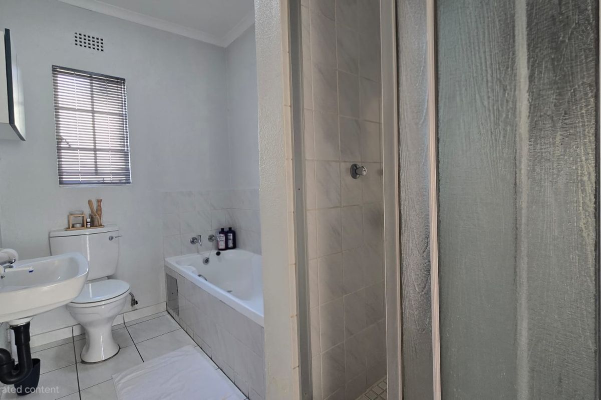 A functional bathroom featuring a pedestal basin, toilet, built-in bathtub, and a separate shower enclosure with tiled finishes.