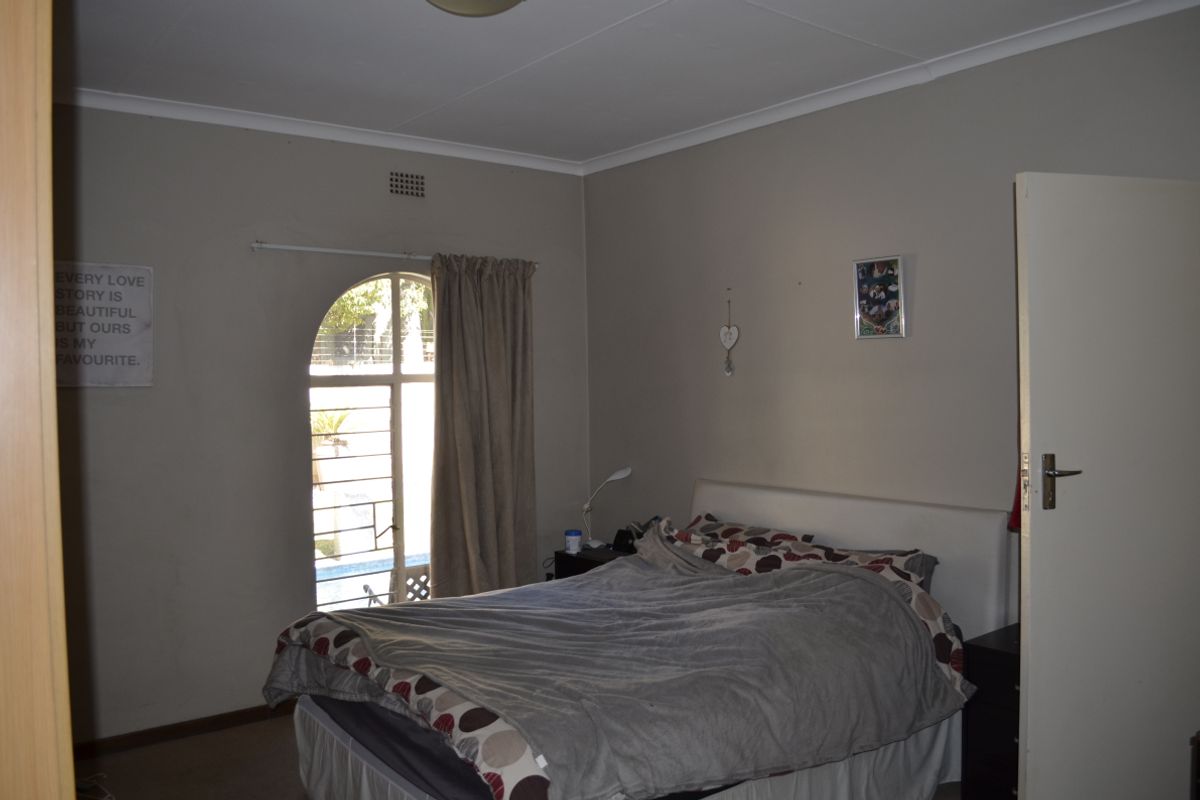 A bedroom featuring an arched window with security bars and neutral wall finishes.