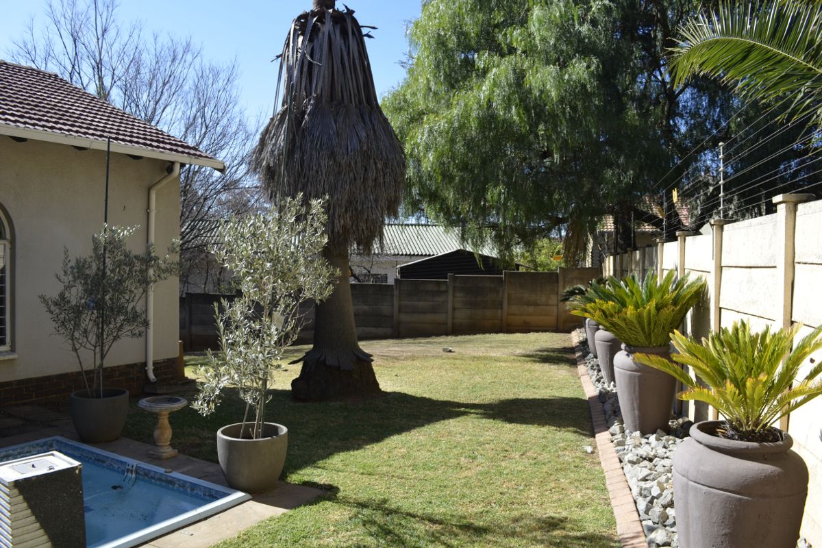 Rear garden area featuring a swimming pool, lawn, and perimeter boundary wall with electric fencing.