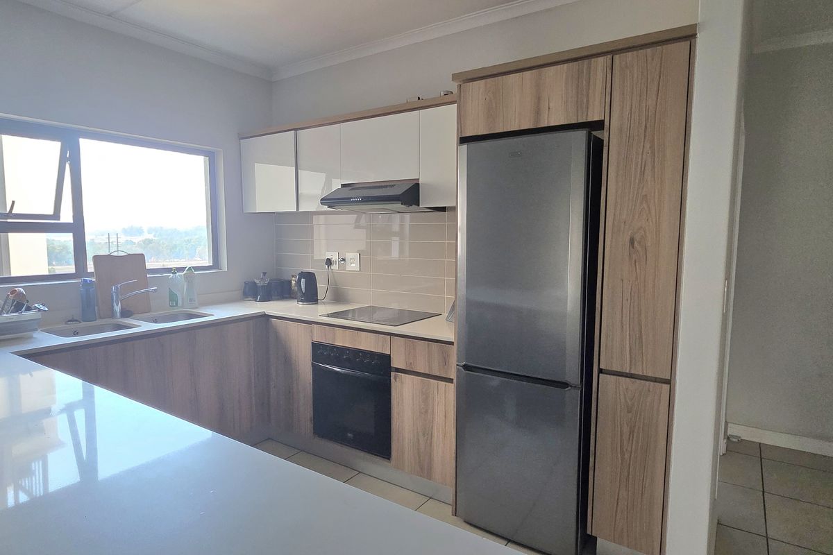 Modern kitchen featuring wood-grain cabinetry, stone countertops, integrated appliances, and a tiled backsplash, offering a clean and functional workspace.