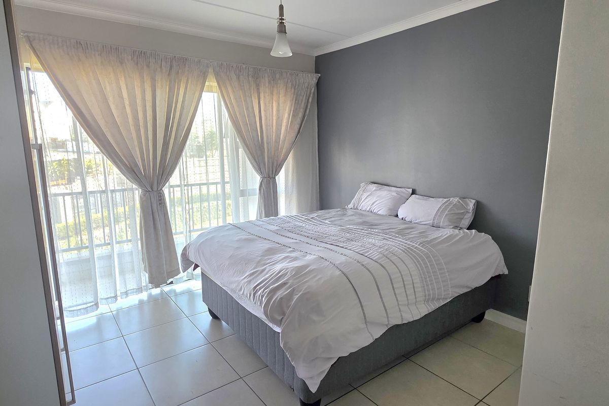 A well-lit bedroom featuring tiled flooring, a built-in cupboard, and a sliding glass door providing access to an outdoor area.