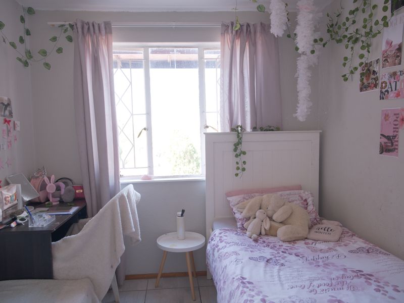 A cozy bedroom featuring tiled flooring and a window that allows for natural light.