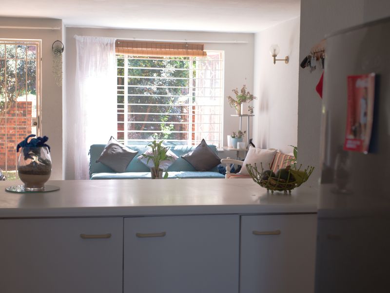 Open plan living area featuring a kitchen with white cabinetry and countertop, flowing into a lounge space with access to an outdoor area.