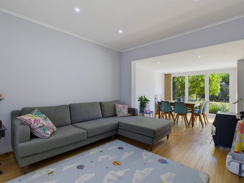 Open plan living and dining area featuring hardwood flooring, recessed downlights, and large sliding glass doors providing access to the garden.
