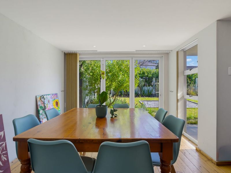 Bright dining room featuring timber flooring and large sliding glass doors that provide direct access to the garden.