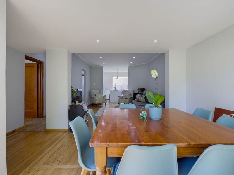 Open plan living and dining area featuring timber flooring and recessed downlighting, with a clear view through to the kitchen space.
