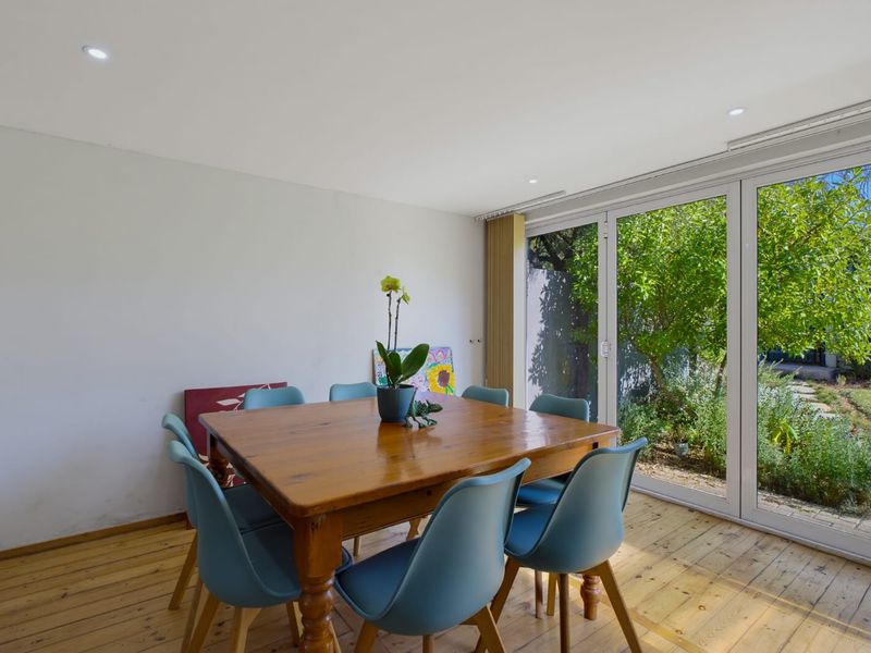 Dining area featuring timber flooring and large sliding glass doors providing direct access to the garden.