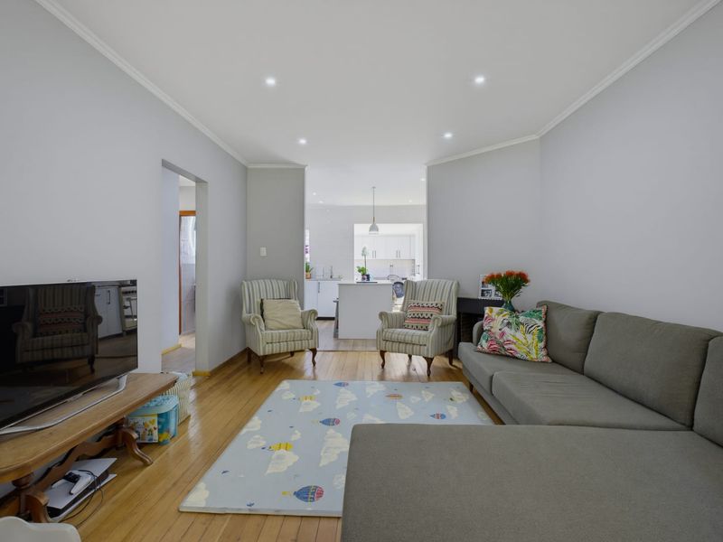 Open-plan living area featuring hardwood flooring, recessed downlights, and a seamless transition into the adjacent kitchen space.