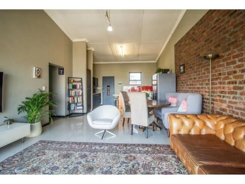 Spacious open-plan living and dining area featuring an exposed brick feature wall, tiled flooring, and a modern kitchen layout.