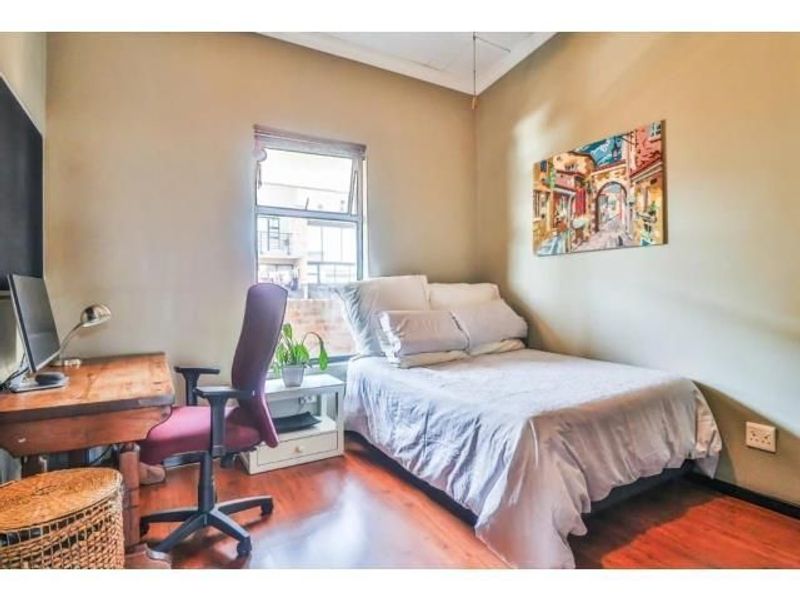 A functional bedroom featuring laminate flooring and a window, providing a comfortable space for rest or study.