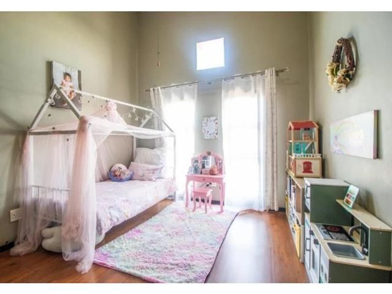 A bright bedroom featuring high ceilings, laminate flooring, and a clerestory window, providing ample natural light and a spacious feel.