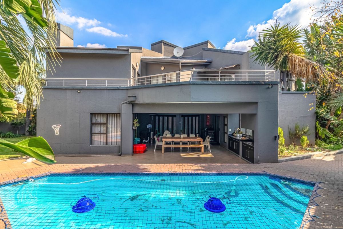 Rear view of the property featuring a swimming pool, covered patio with built-in cabinetry, and an upper-level balcony.