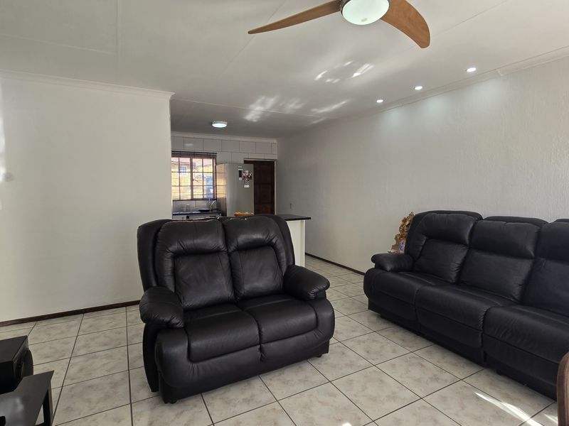 Open-plan living area featuring tiled flooring, recessed lighting, a ceiling fan, and a functional kitchen space with a breakfast counter.