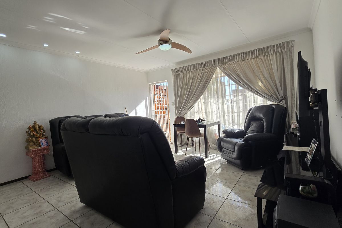 A bright living room featuring tiled flooring, a ceiling fan, and recessed lighting, with direct access to an outdoor area through a security gate.