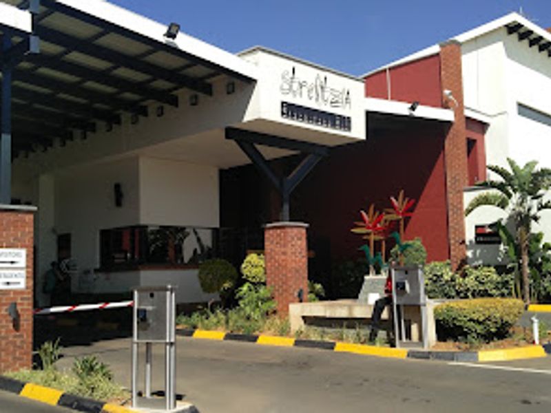 The main entrance to the Strelitzia apartment complex, featuring a secure boom gate, guard booth, and a covered driveway canopy.