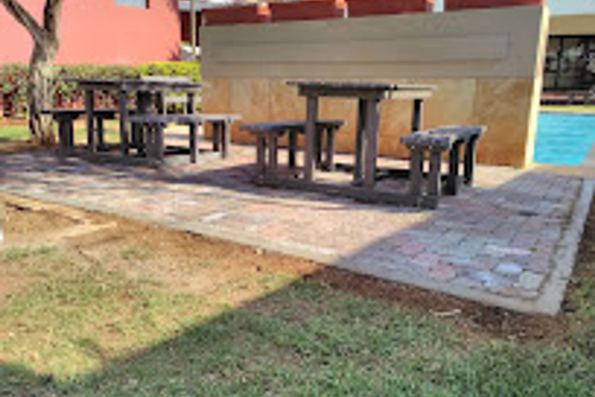 Outdoor pool area featuring a paved patio space, retaining wall, and access to the swimming pool.