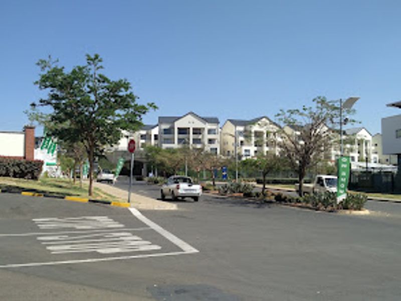 A street-level view showing the approach to the apartment complex with paved roads and landscaped surroundings.