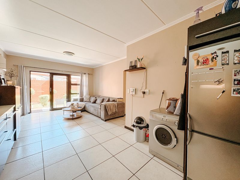 Open-plan living area featuring tiled flooring and a sliding glass door leading to an outdoor space, integrated with a functional kitchen layout.