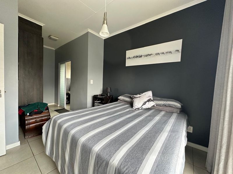 A well-maintained bedroom featuring tiled flooring, a built-in cupboard, and a modern pendant light fixture.
