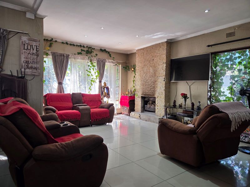 Spacious living room featuring a prominent stone-clad fireplace, large windows for natural light, and neutral tiled flooring throughout.