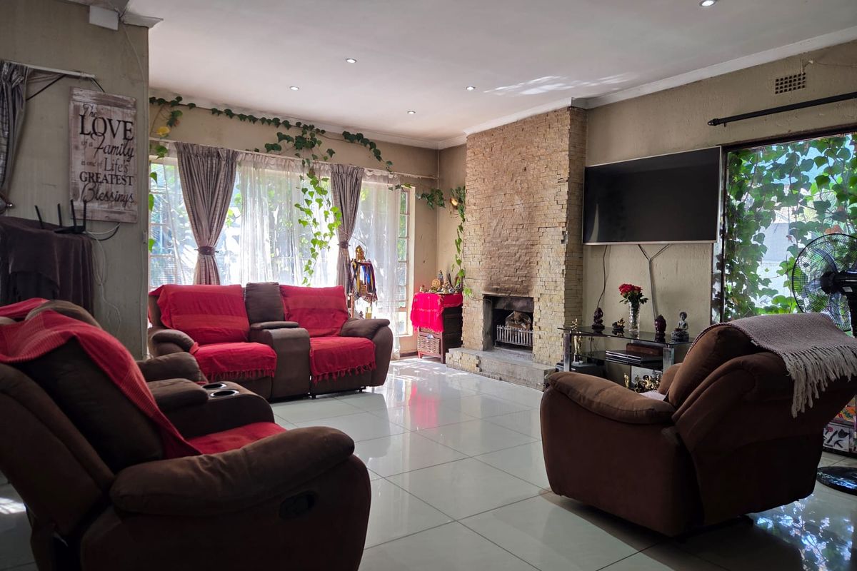Spacious living room featuring a prominent stone-clad fireplace, large windows for natural light, and neutral tiled flooring throughout.