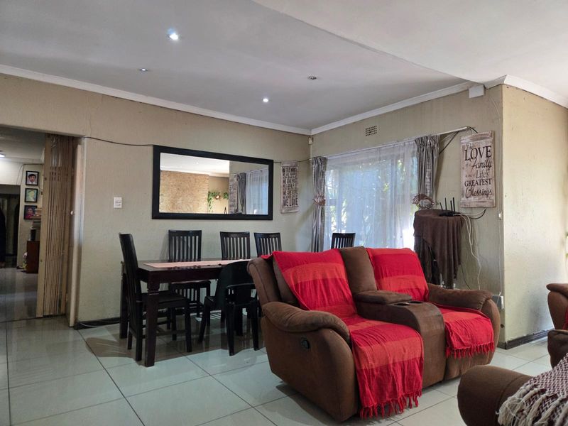 Open plan living and dining area featuring tiled flooring and recessed downlighting, offering a functional space for family gatherings.