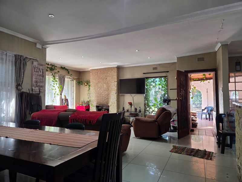 Spacious open-plan living and dining area featuring a stone-clad fireplace, tiled flooring, and direct access to an outdoor patio through a sliding glass door.