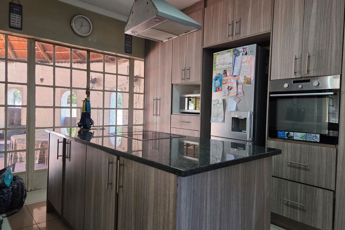 Modern kitchen featuring a central island with granite countertops, built-in oven, extractor fan, and ample cabinetry, with direct access to an outdoor patio area.