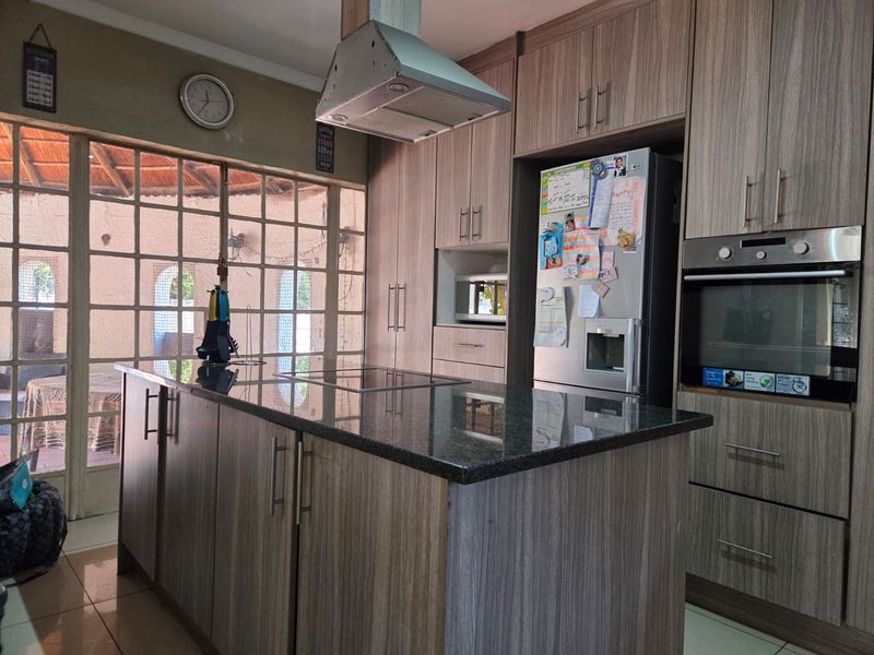 Modern kitchen featuring a central island with granite countertops, built-in oven, extractor fan, and ample cabinetry, with direct access to an outdoor patio area.