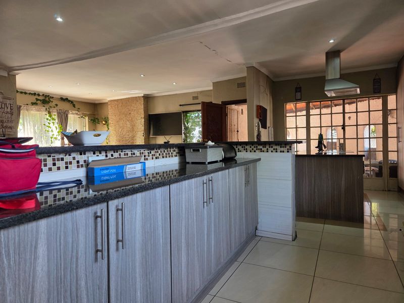 Open-plan kitchen and living area featuring modern cabinetry, granite countertops, a stone feature wall, and tiled flooring throughout.