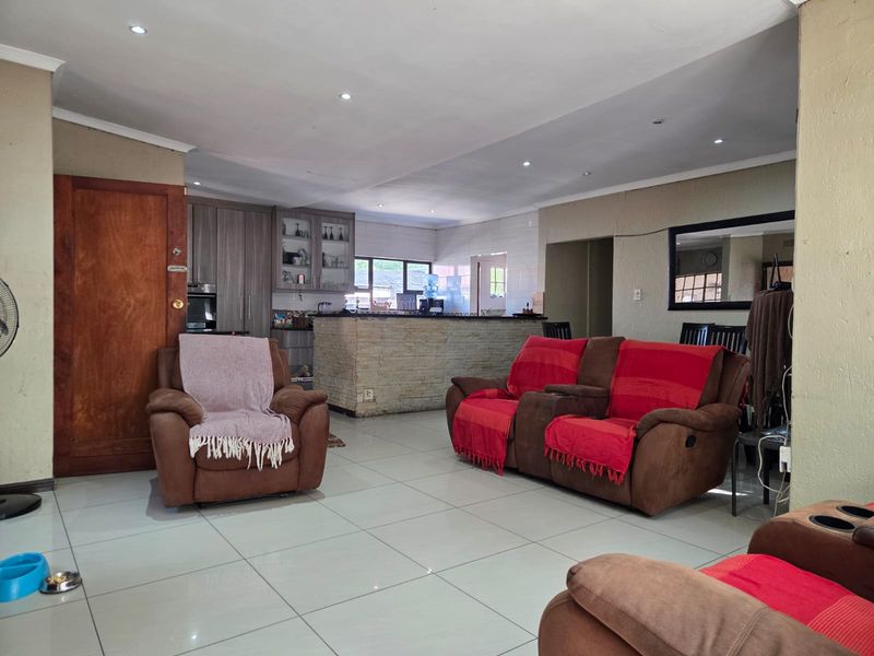 Spacious open-plan living area featuring tiled floors, recessed lighting, and a stone-clad breakfast bar connecting to the kitchen.