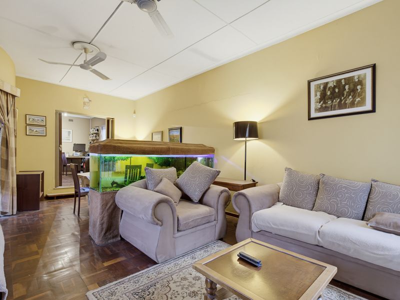 A living room featuring parquet flooring and dual ceiling fans, with a view through to an adjacent room.