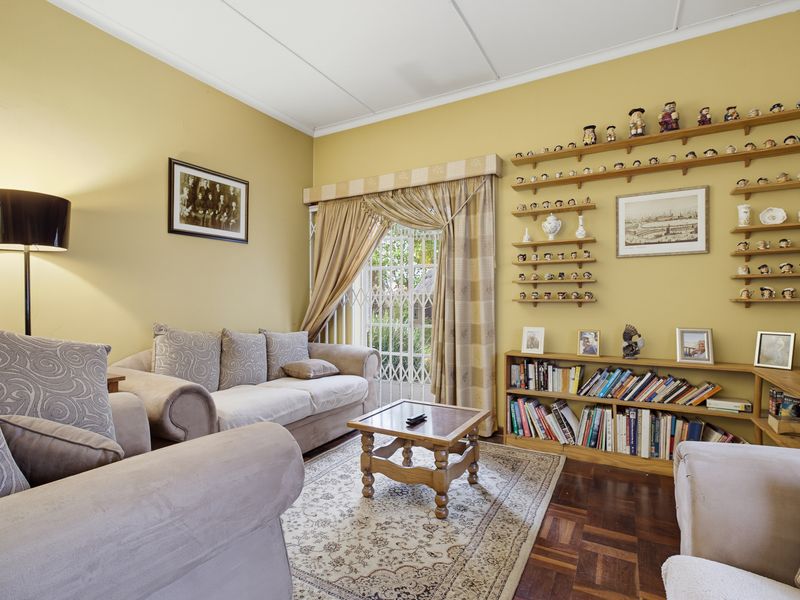 A comfortable living room featuring classic parquet flooring, built-in wall shelving, and a security gate leading to the exterior.
