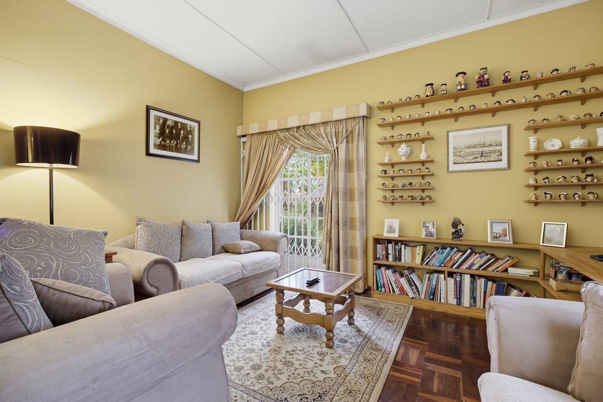 A comfortable living room featuring classic parquet flooring, built-in wall shelving, and a security gate leading to the exterior.