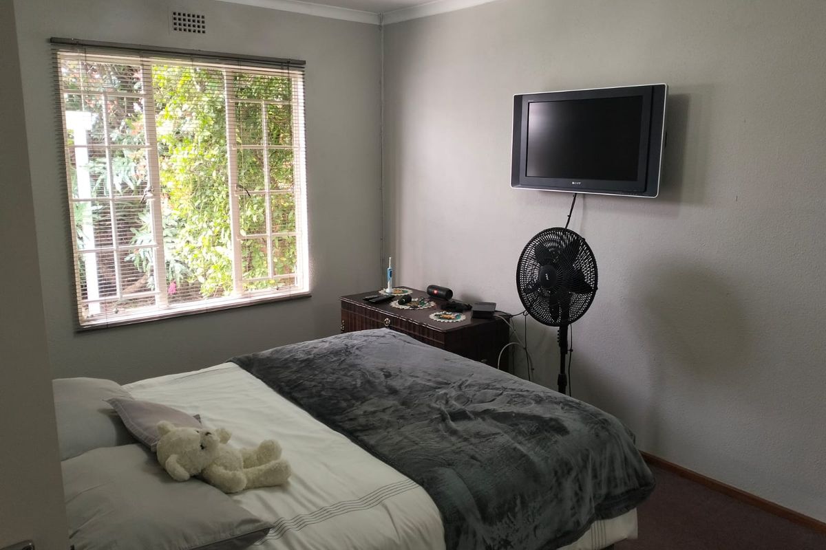 A functional bedroom featuring a window with security bars and wall-mounted television infrastructure.