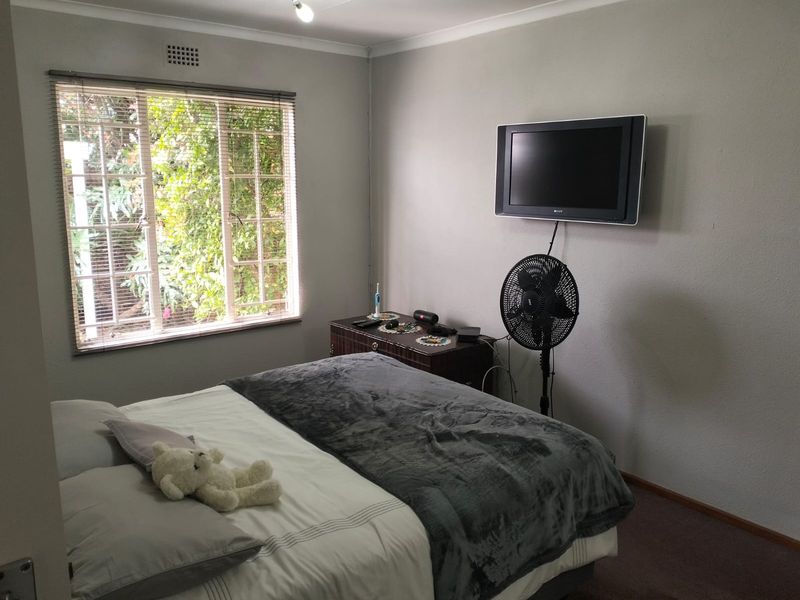 A functional bedroom featuring a window with security bars and wall-mounted television infrastructure.
