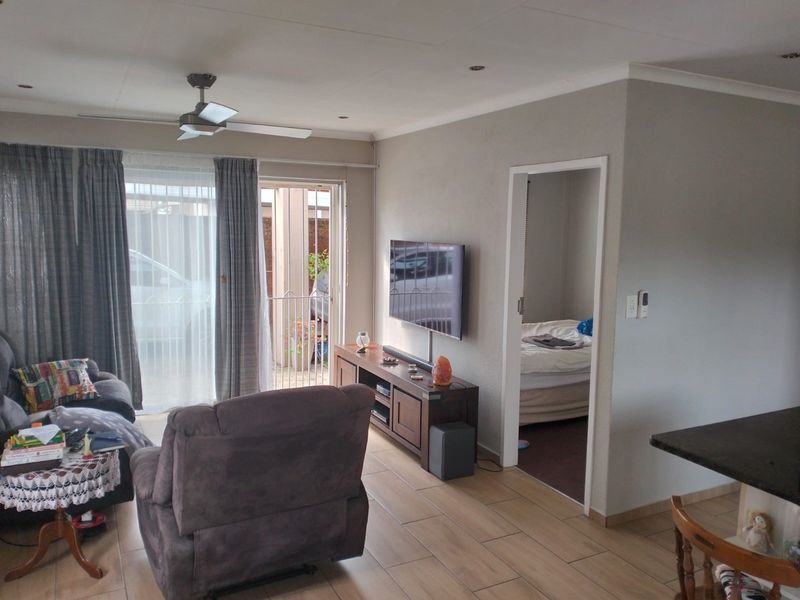 A comfortable living room featuring tiled flooring, recessed lighting, a ceiling fan, and direct access to an outdoor patio area through sliding glass doors.