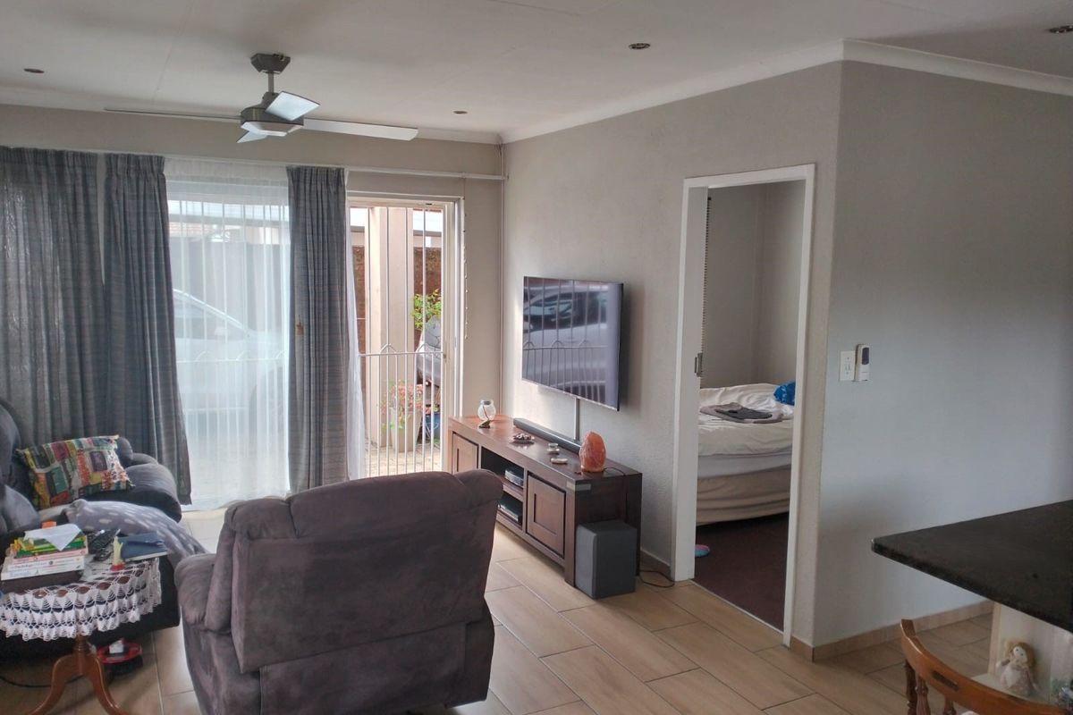 A comfortable living room featuring tiled flooring, recessed lighting, a ceiling fan, and direct access to an outdoor patio area through sliding glass doors.