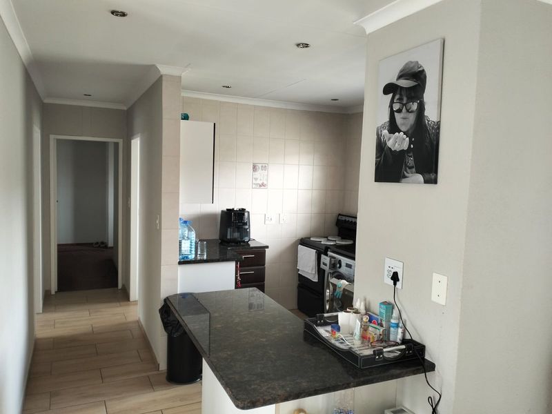 A functional kitchen area featuring granite countertops, tiled backsplash, and built-in cabinetry, with a breakfast bar extending into the adjacent living space.