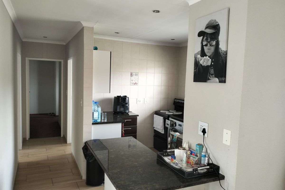 A functional kitchen area featuring granite countertops, tiled backsplash, and built-in cabinetry, with a breakfast bar extending into the adjacent living space.