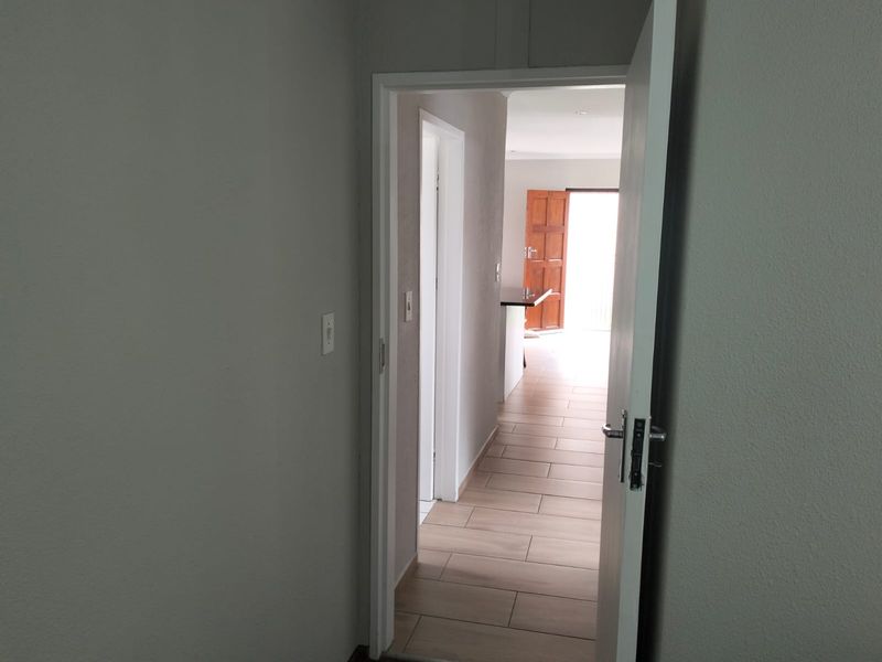 A view through an open doorway into a tiled hallway leading towards an exterior entrance.