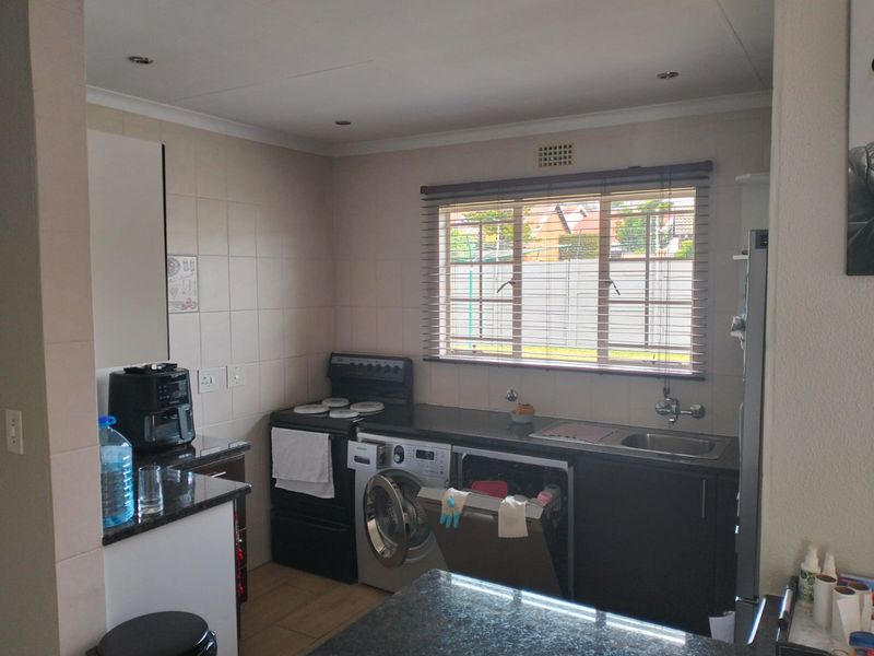 A functional kitchen featuring granite countertops, tiled backsplash, and integrated cabinetry with space for laundry appliances.
