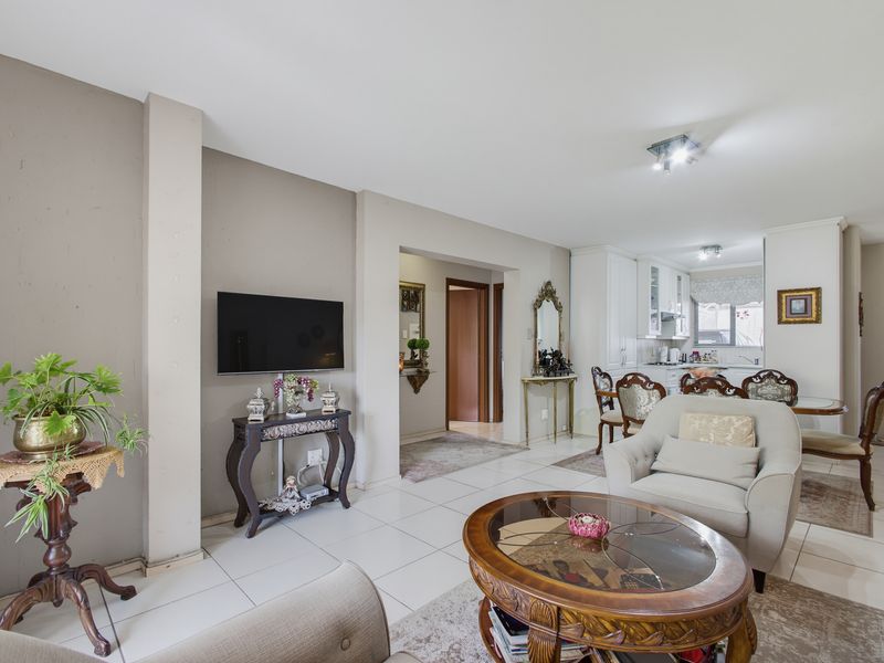 Spacious open-plan living and dining area featuring neutral tiled flooring, recessed lighting, and a seamless transition into the functional kitchen space.