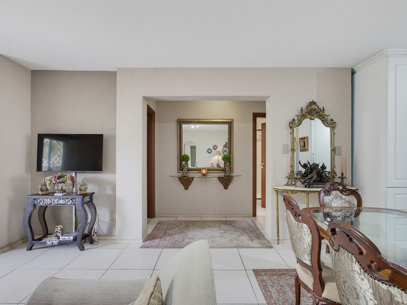 A living area featuring tiled flooring and neutral wall finishes, providing a functional space with direct access to adjacent rooms.