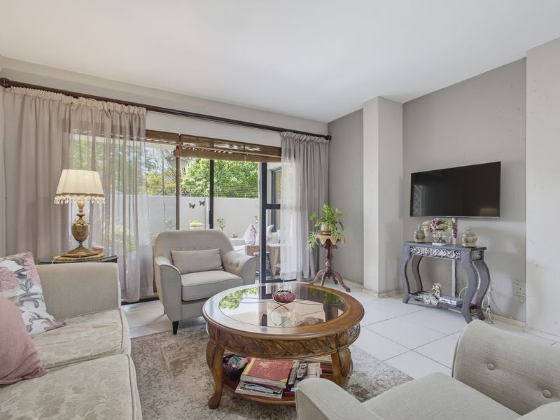 A bright living room featuring tiled flooring and large sliding glass doors that provide direct access to the outdoor patio area.