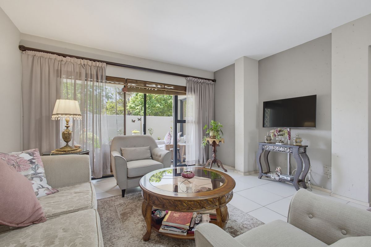 A bright living room featuring tiled flooring and large sliding glass doors that provide direct access to the outdoor patio area.