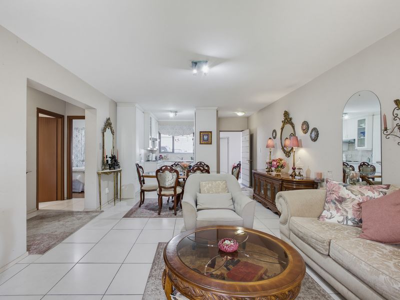 Spacious open-plan living and dining area featuring neutral tiled flooring, recessed lighting, and a seamless flow into the adjacent kitchen space.