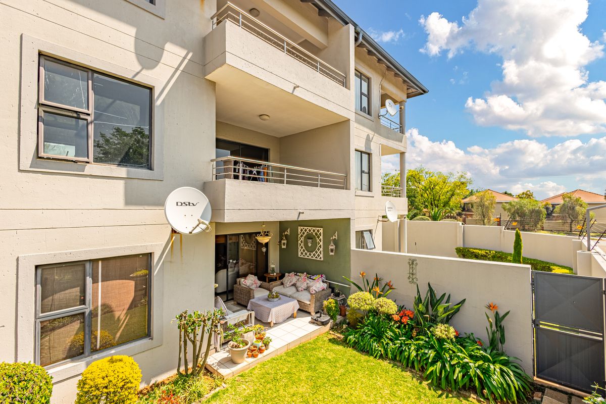 Rear view of the townhouse featuring a private garden, tiled patio area, and multiple balconies with sliding door access.