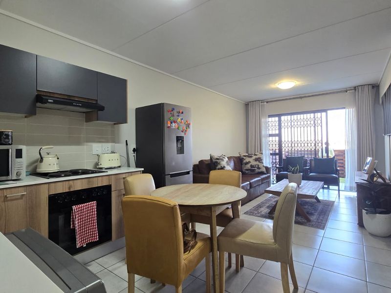 Open-plan living area featuring a modern kitchen with built-in cabinetry, tiled flooring, and direct access to an outdoor patio through sliding doors.
