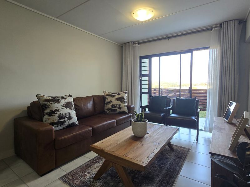 A comfortable living room featuring tiled flooring and a large sliding glass door that provides natural light and access to the outdoor area.